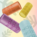 Load image into Gallery viewer, All four shades of Noz reef safe, cutely-free sunscreen sticks falling, frozen in mid air against pink, yellow and blue ombre backdrop.
